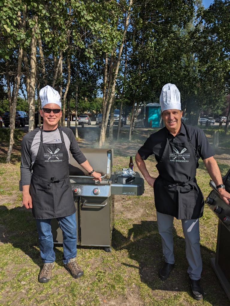 Dave and Ken Ratcliffe grilling and wearing Grill Master aprons and chefs hats