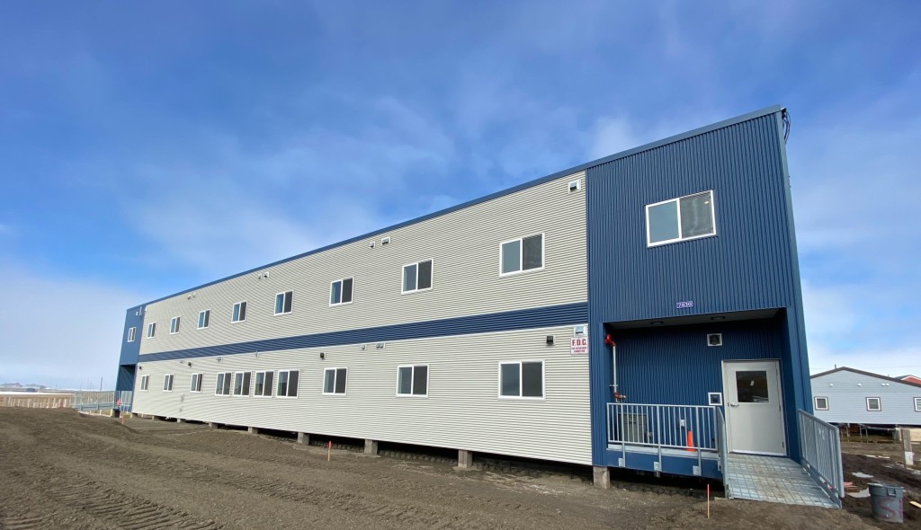 White and blue elevated building with metal grate walls